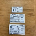 Three labels are sitting on top of a wooden table.
