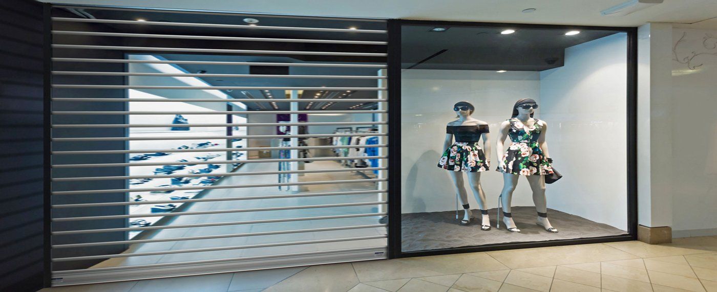 Two mannequins are standing in front of a store window.