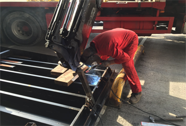A man in a red jumpsuit is welding a piece of metal