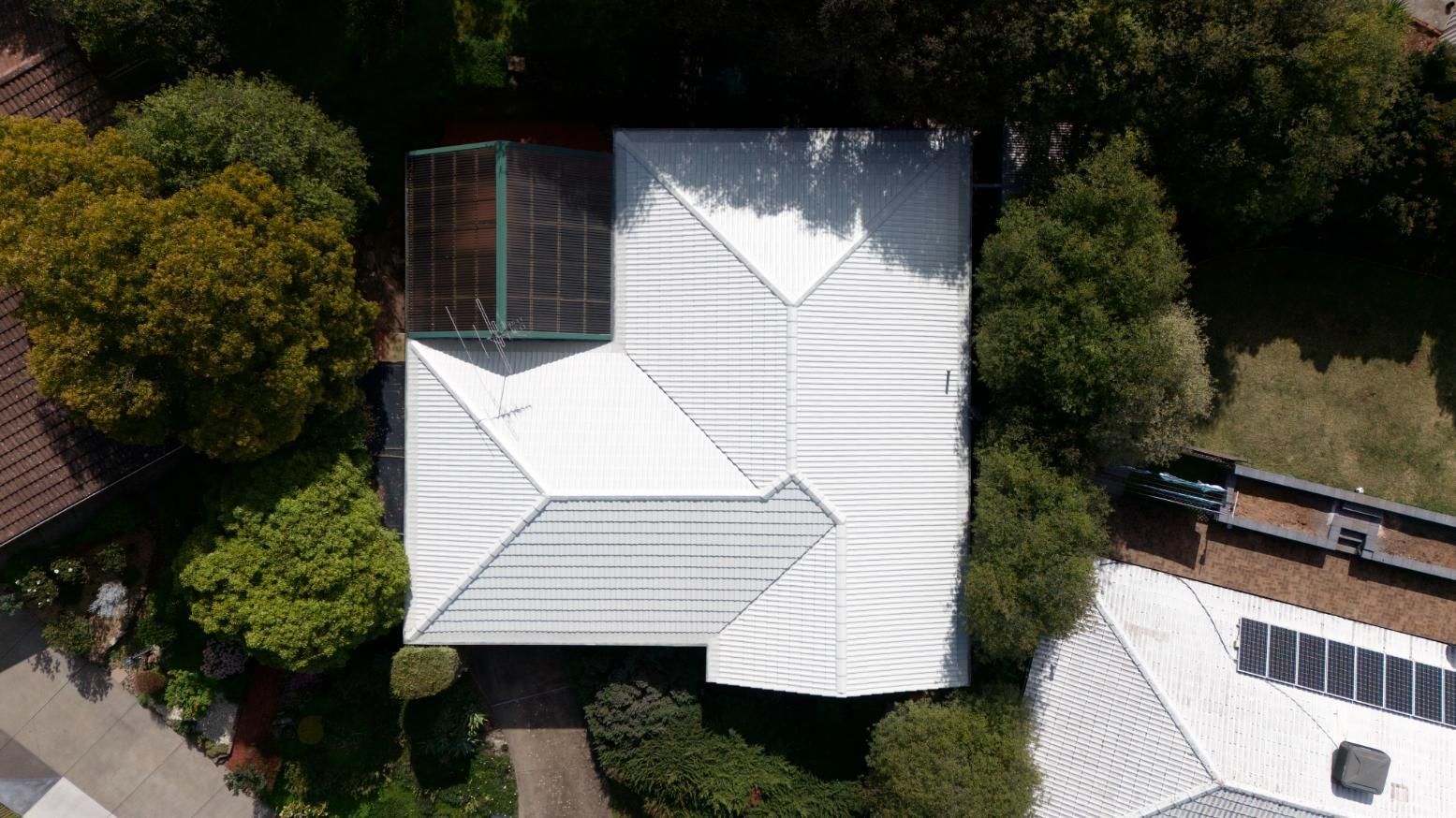 Aerial view of white-roofed houses surrounded by dense green trees.