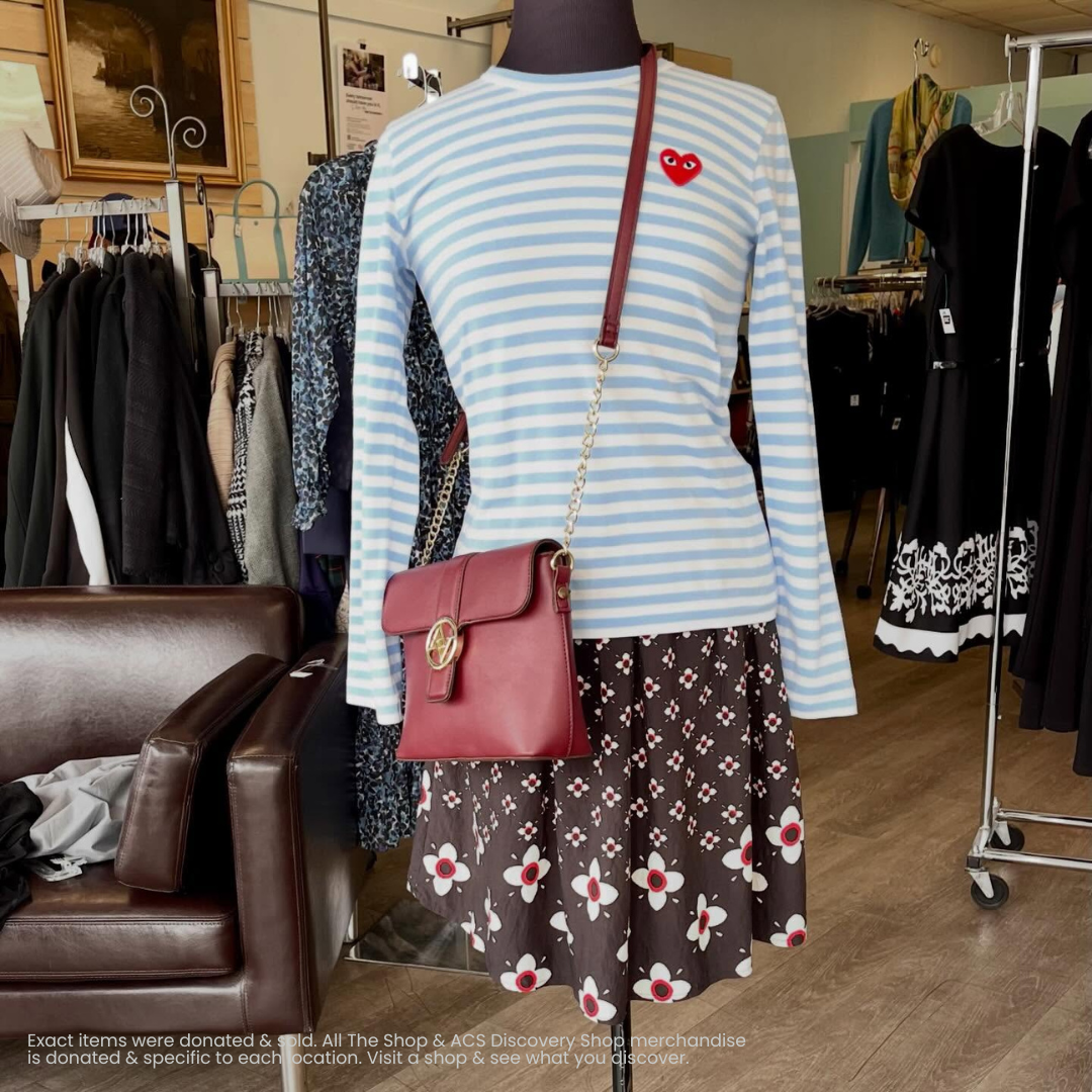 Striped light-blue top with brown floral skirt and burgundy crossbody bag on a store mannequin