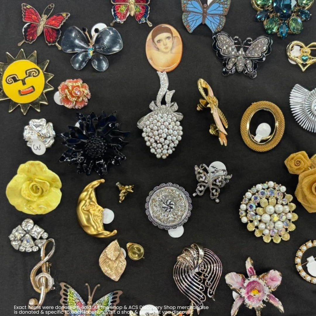 Assorted colorful brooches and pins displayed on a dark background