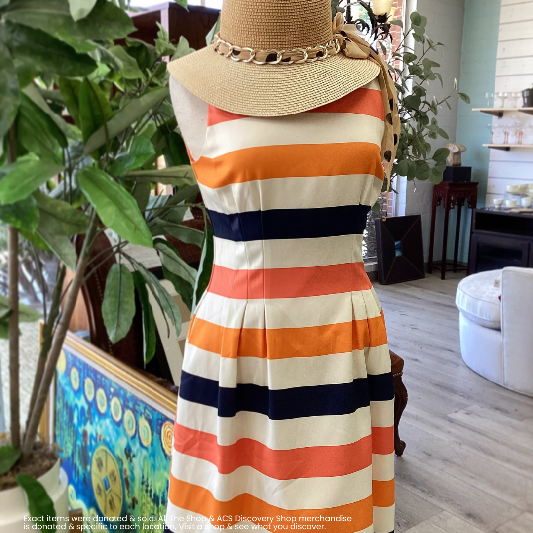 Striped orange, navy, and white sleeveless dress on a mannequin in a bright room, topped with a straw hat