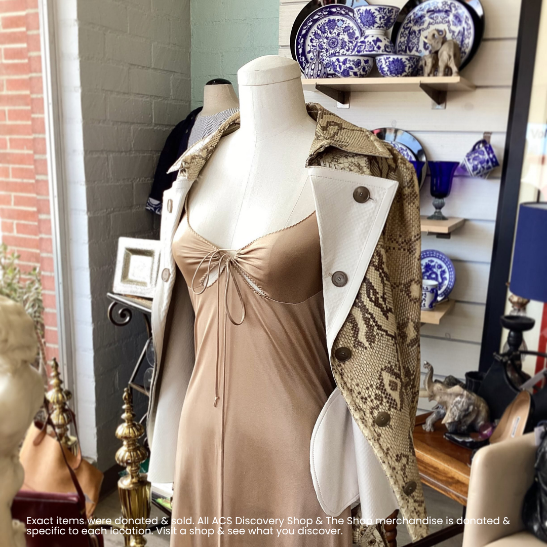 Mannequin wearing a tan dress and snake-print coat in a boutique display