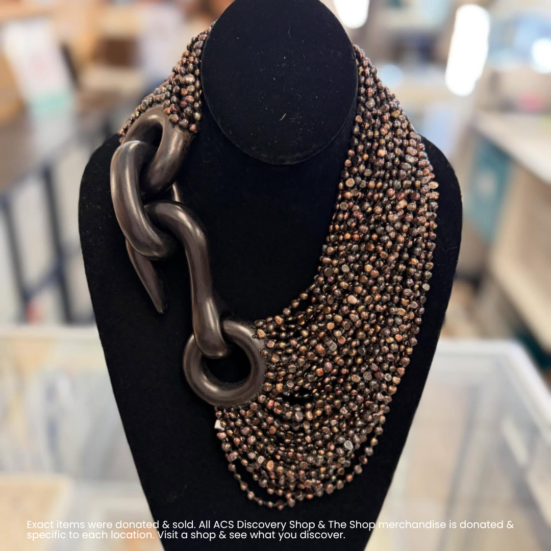 Black mannequin displaying a chunky chain necklace with layered bronze and black beads