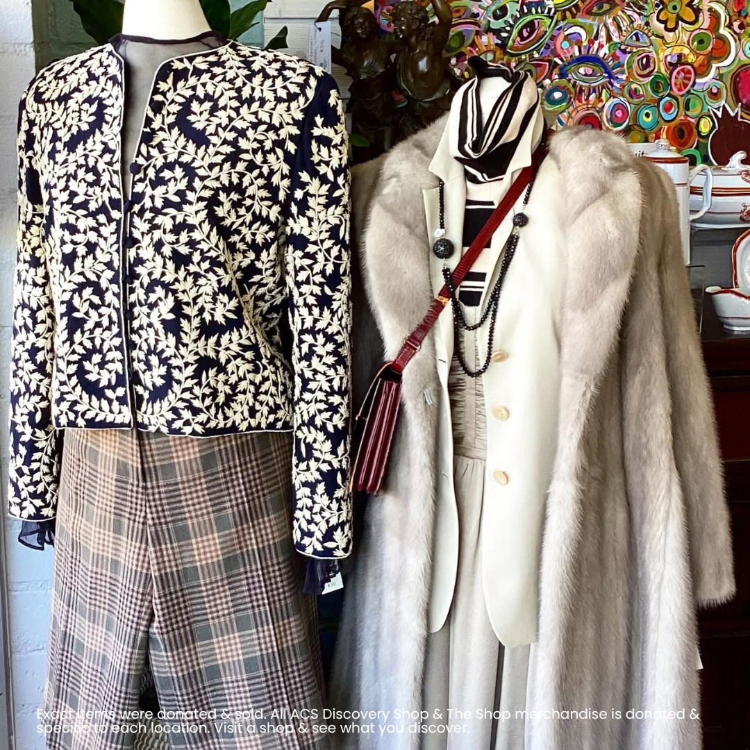Mannequins in patterned jacket and plaid skirt beside a white coat and accessories in a boutique window