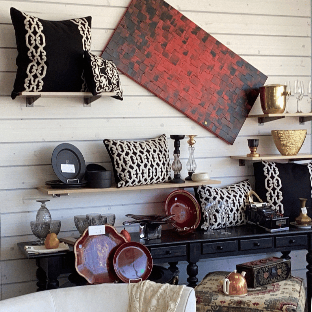 Assorted framed floral paintings, ceramics, and tableware displayed in an art shop window