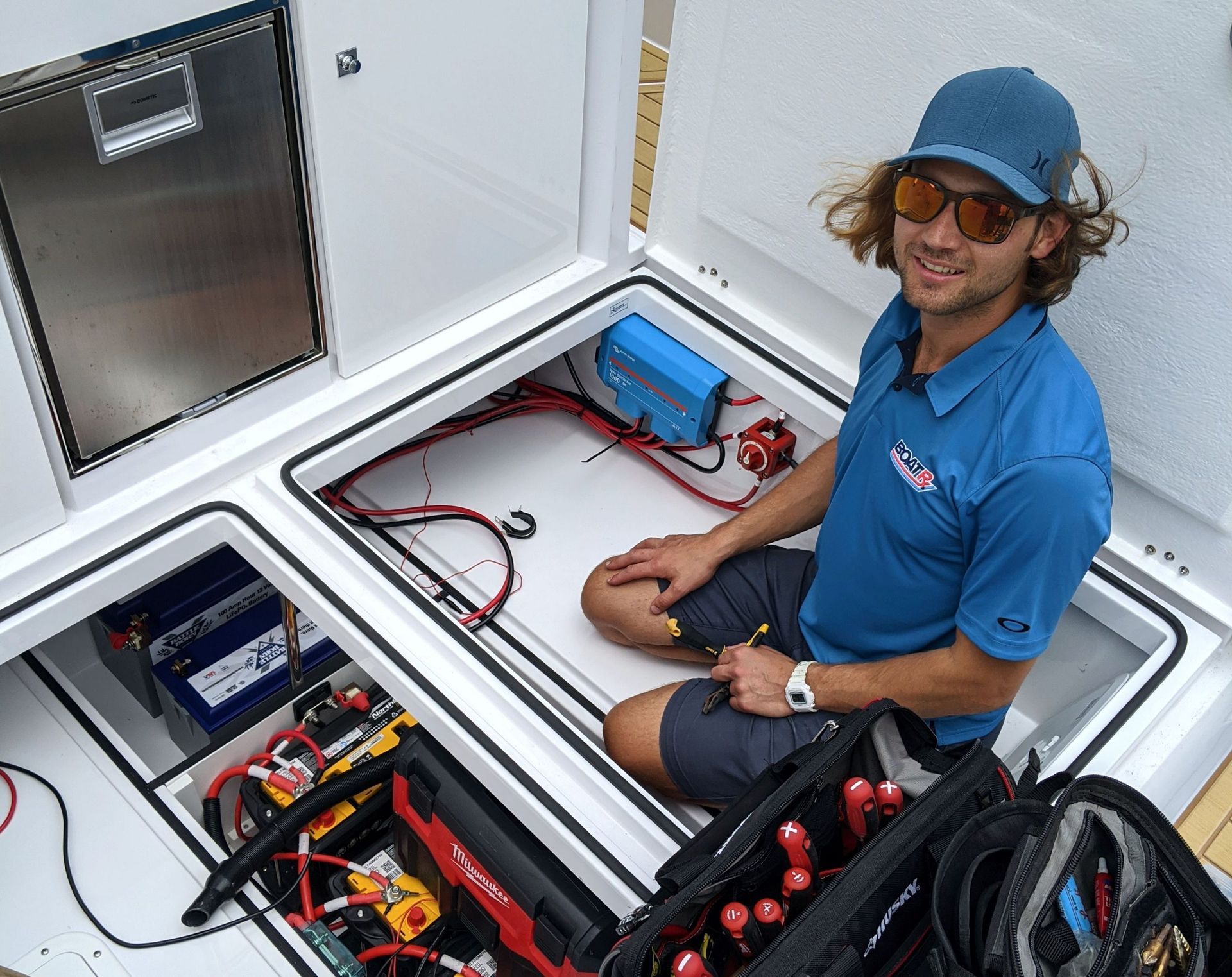A man in a blue shirt is working on a boat electrical section