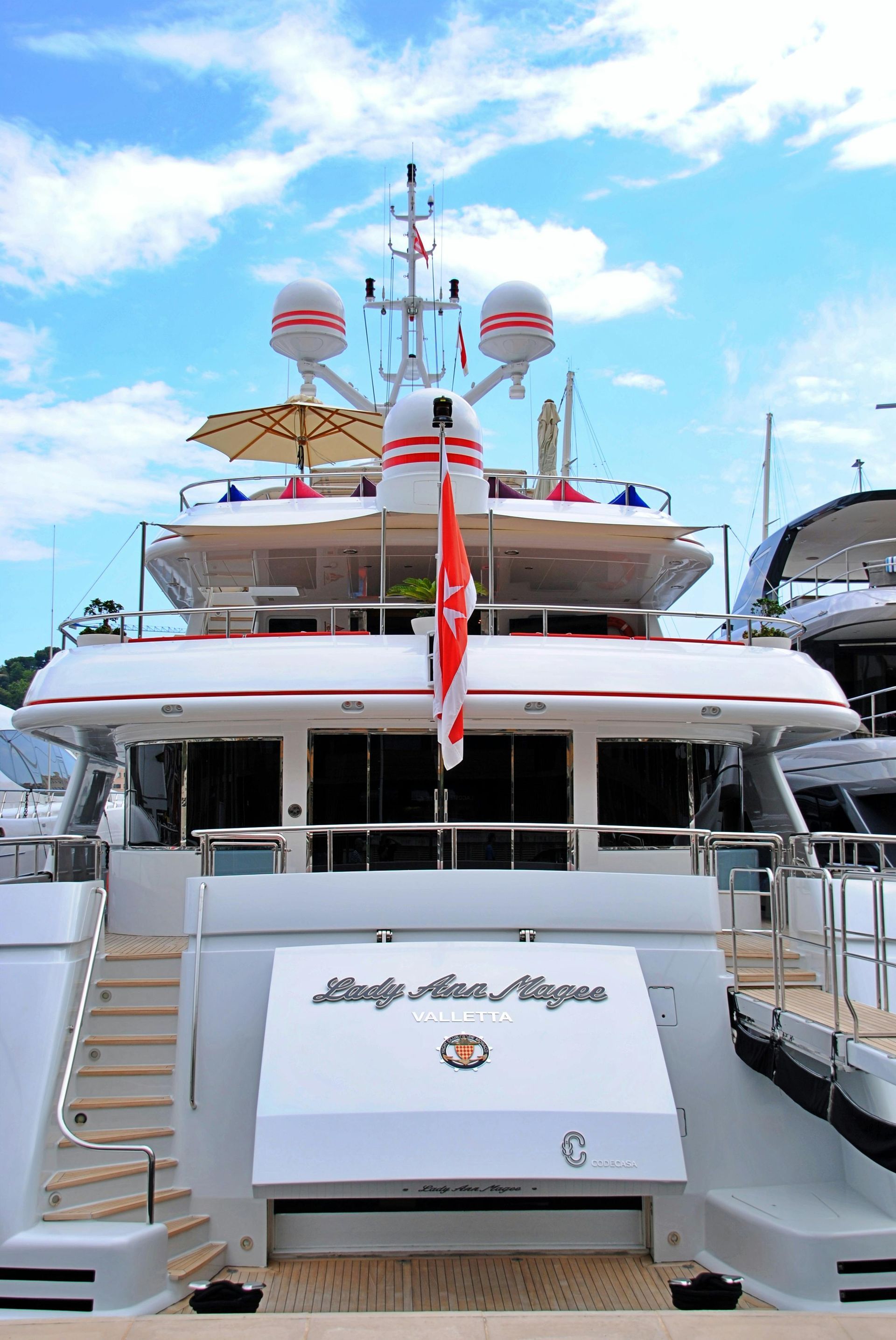 A large white yacht with a red flag on top of it