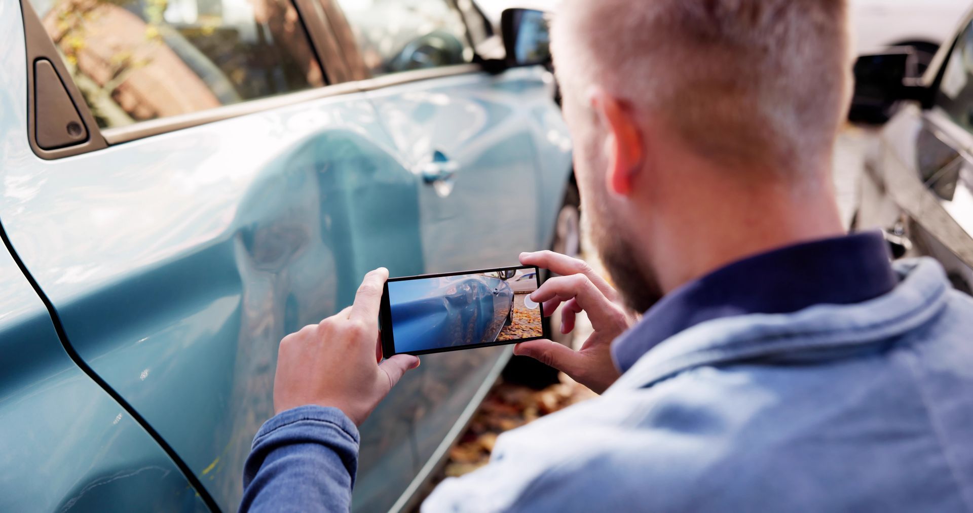 Man photographing vehicle damage to preserve evidence after a car accident