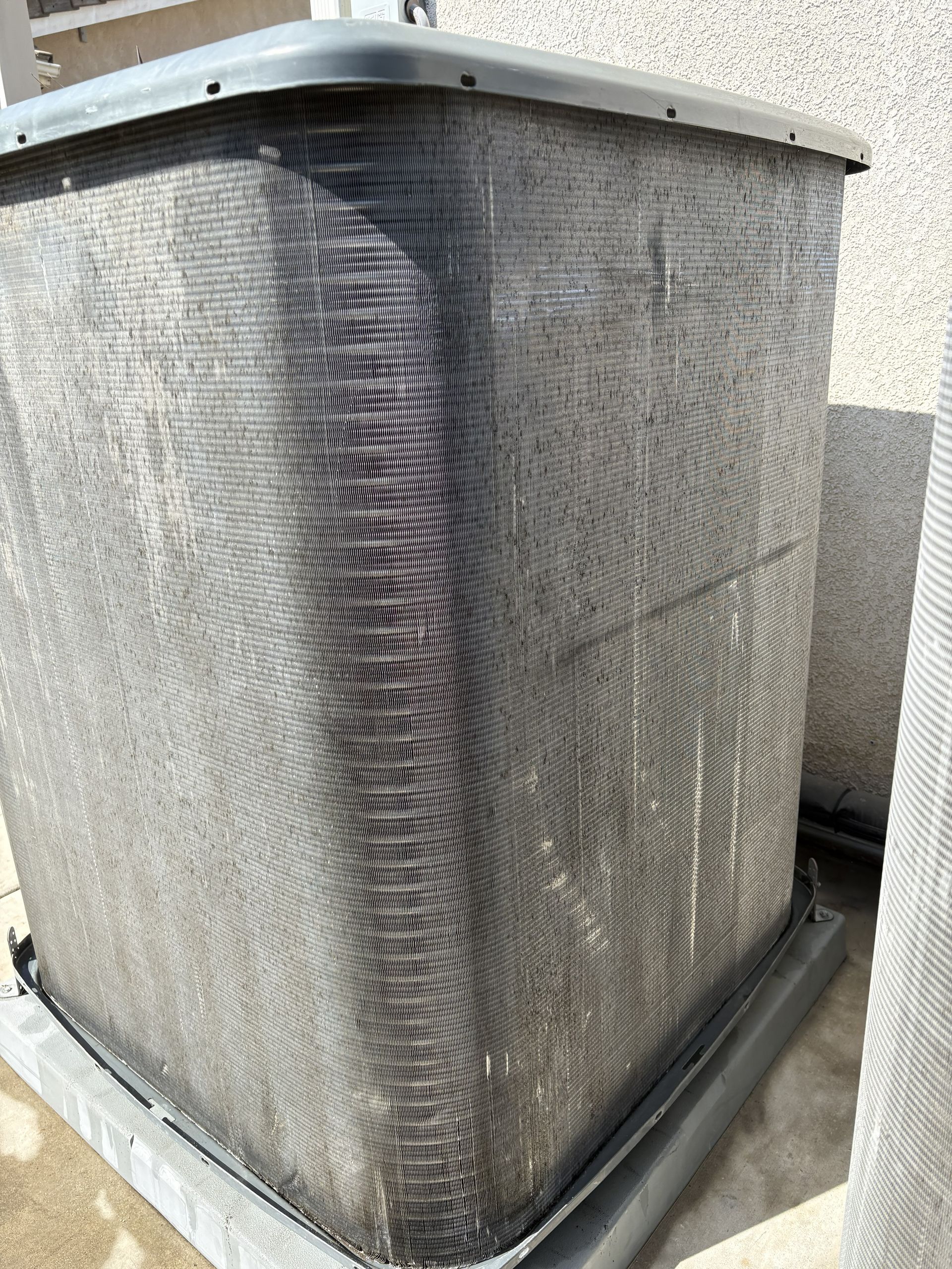 Dirty outdoor HVAC condenser unit with a bent front grille panel
