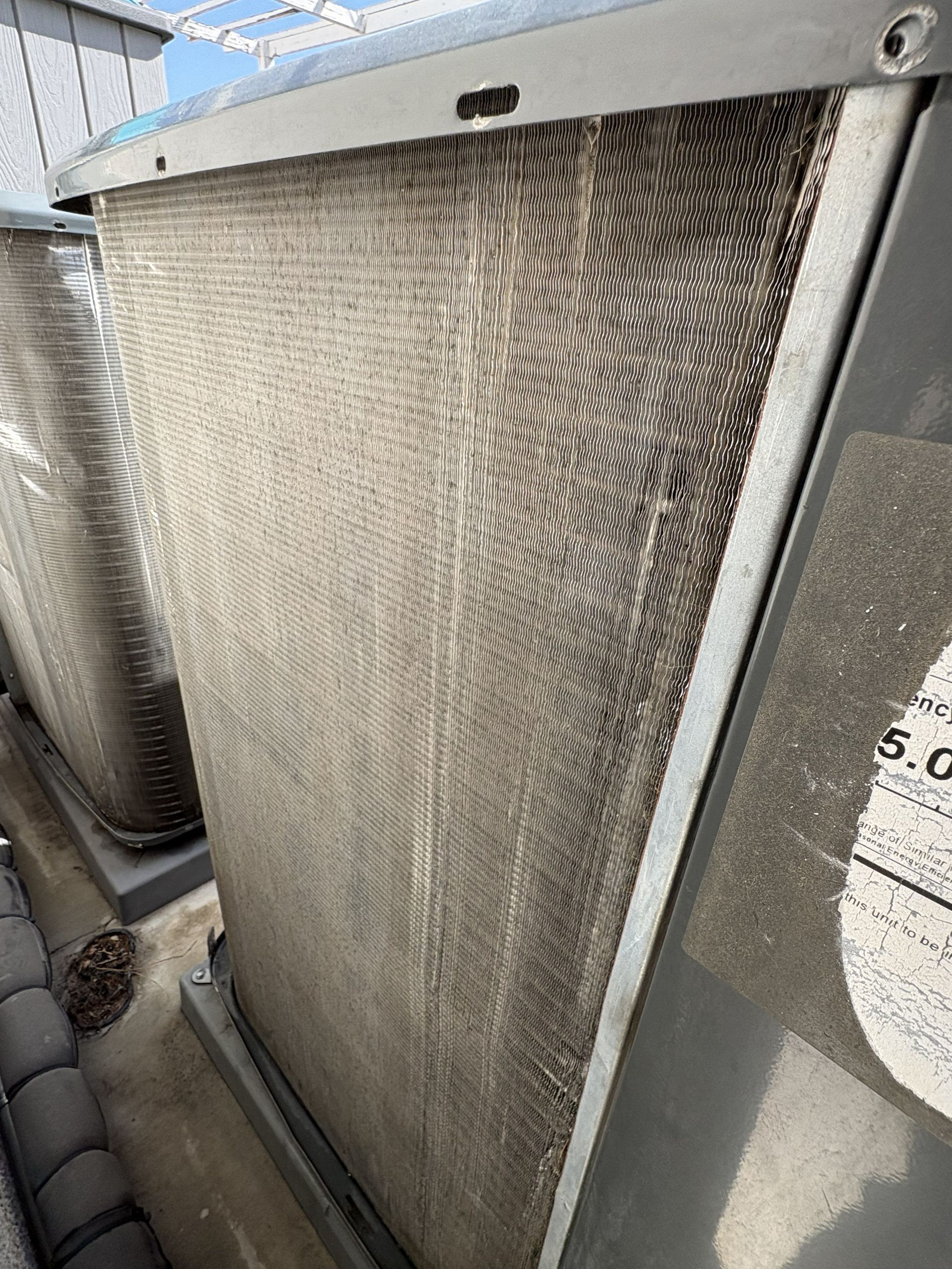 Close-up of a weathered metal cooling tower with a gray mesh or radiator panel outdoors