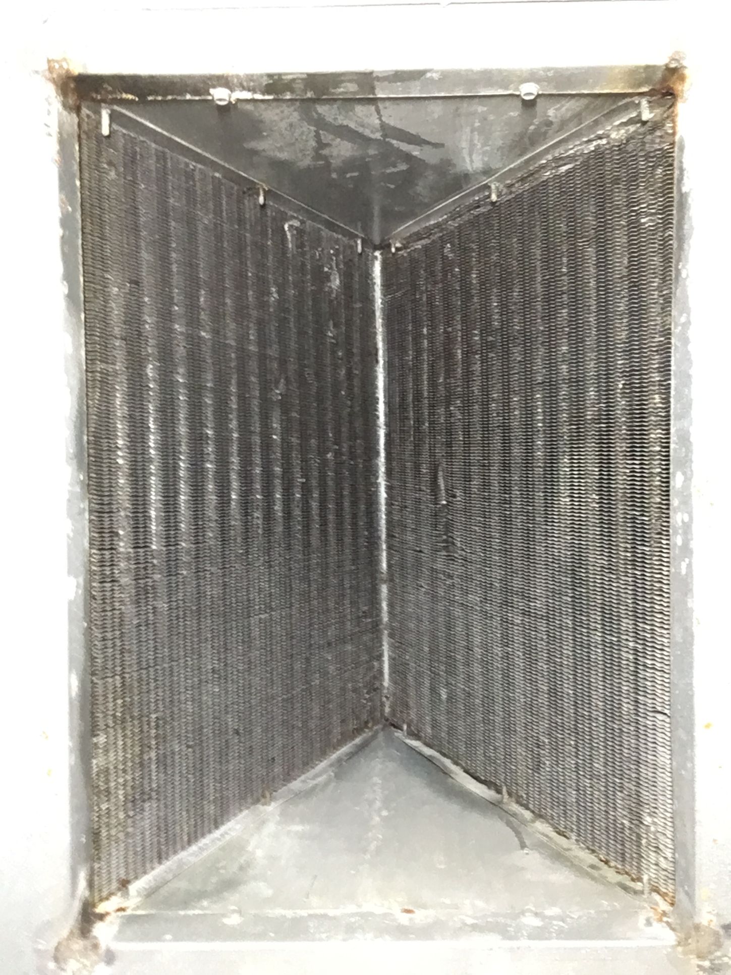 Metal vent or duct interior with dark ribbed sides and a triangular opening at the bottom.