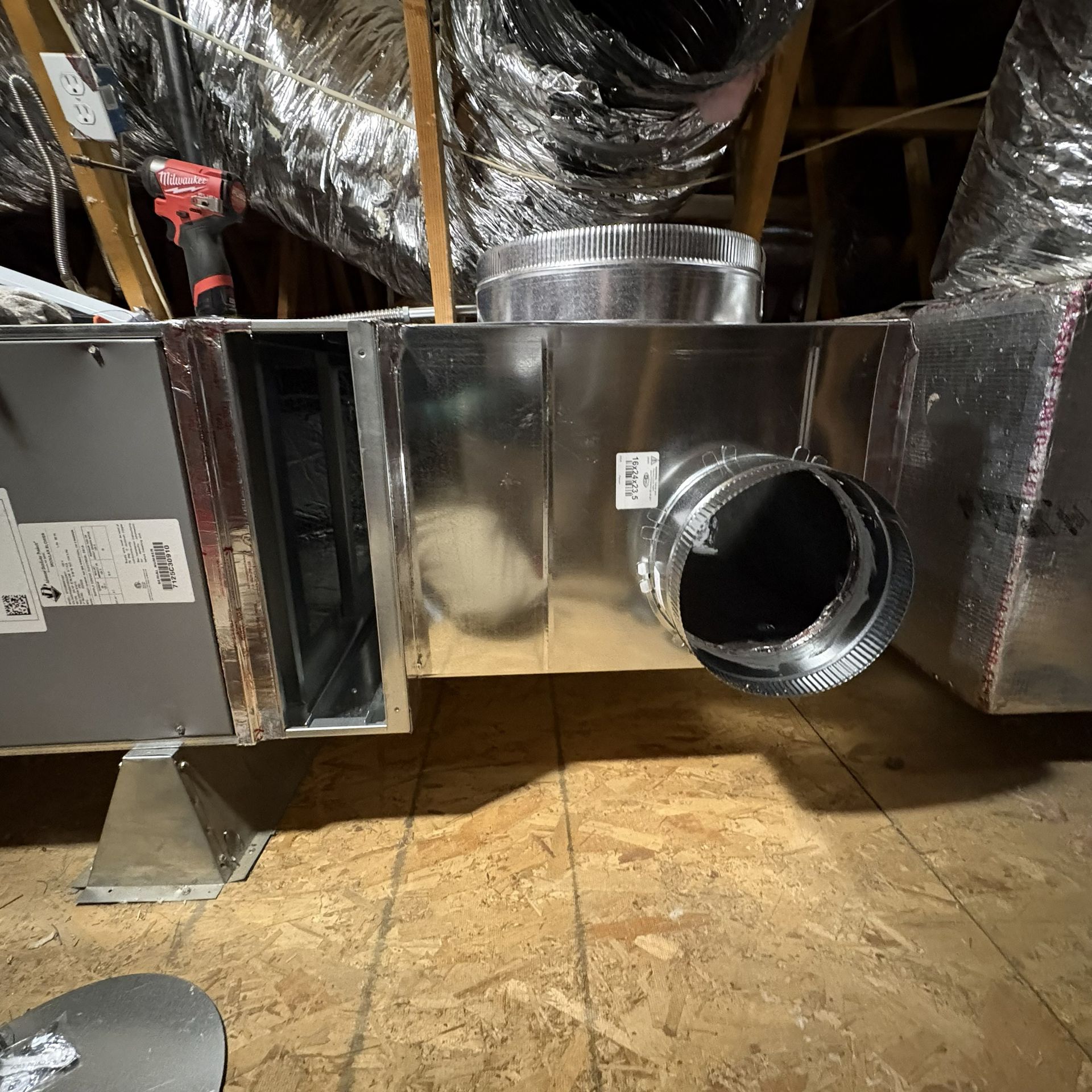 HVAC ductwork in an attic, with shiny metal vents and insulation around the system