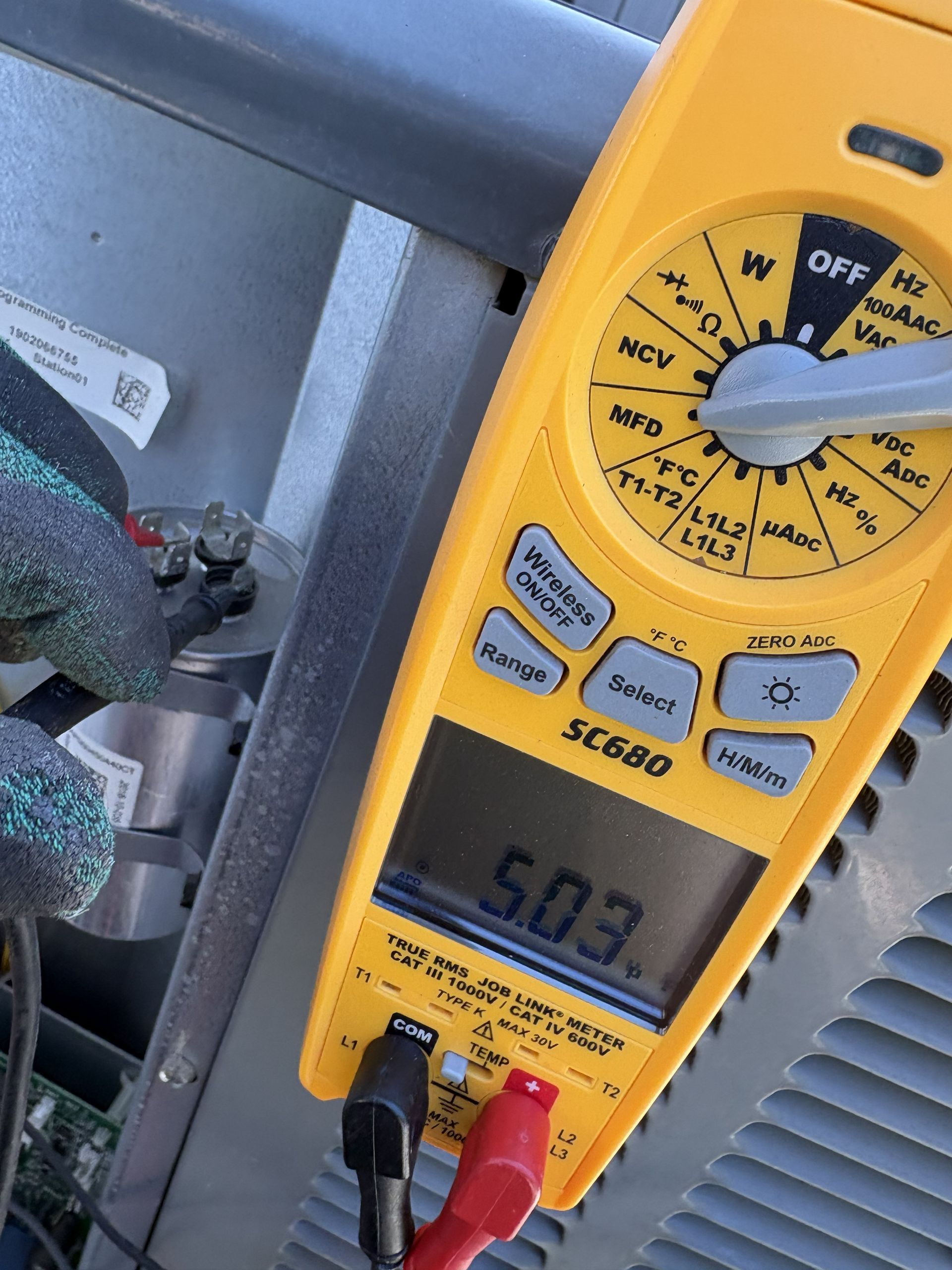 Yellow digital multimeter showing 50.3, with black and red probes attached.