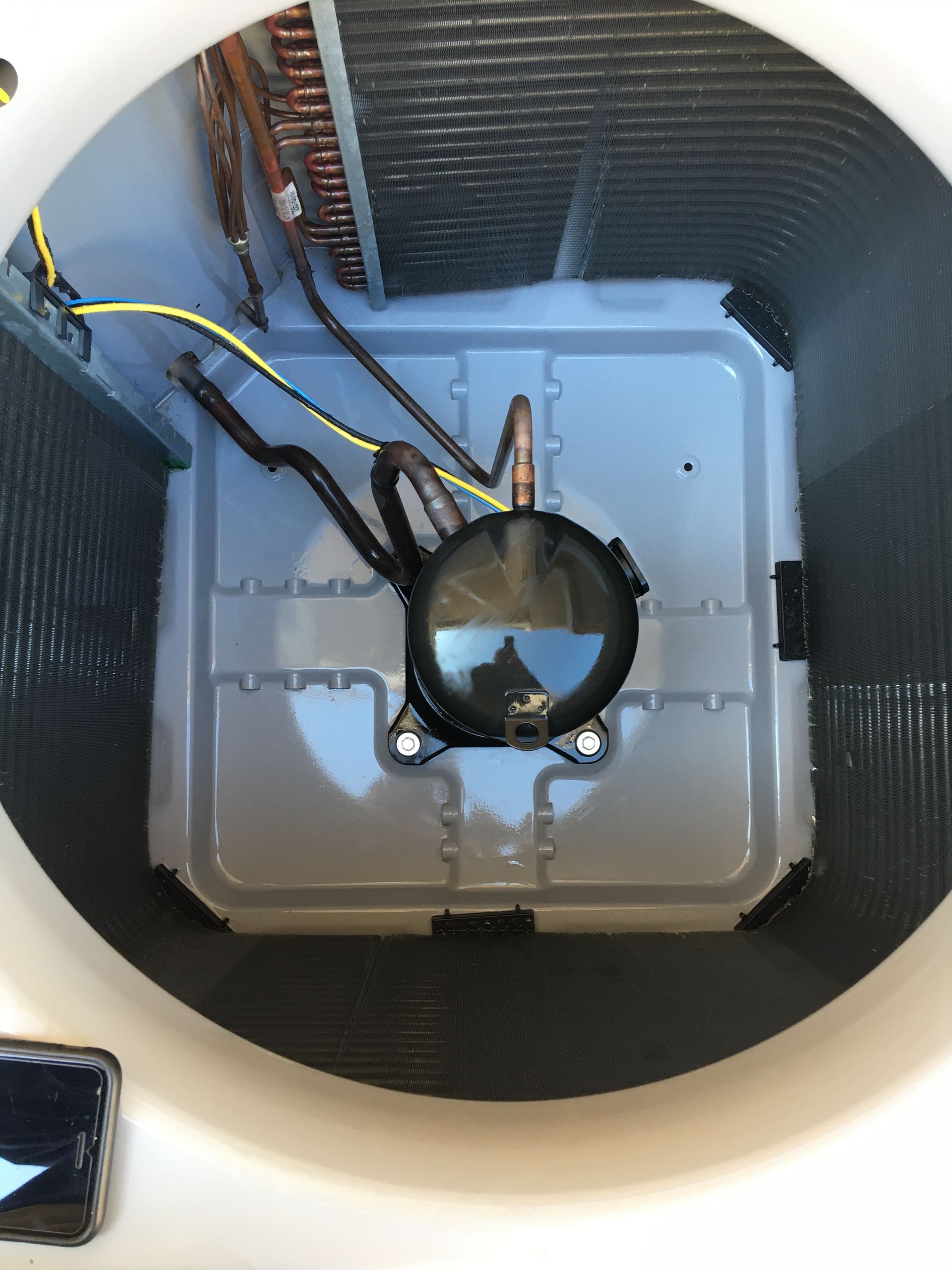 Top-down view of a utility box with black wires and a round connector inside a white circular housing