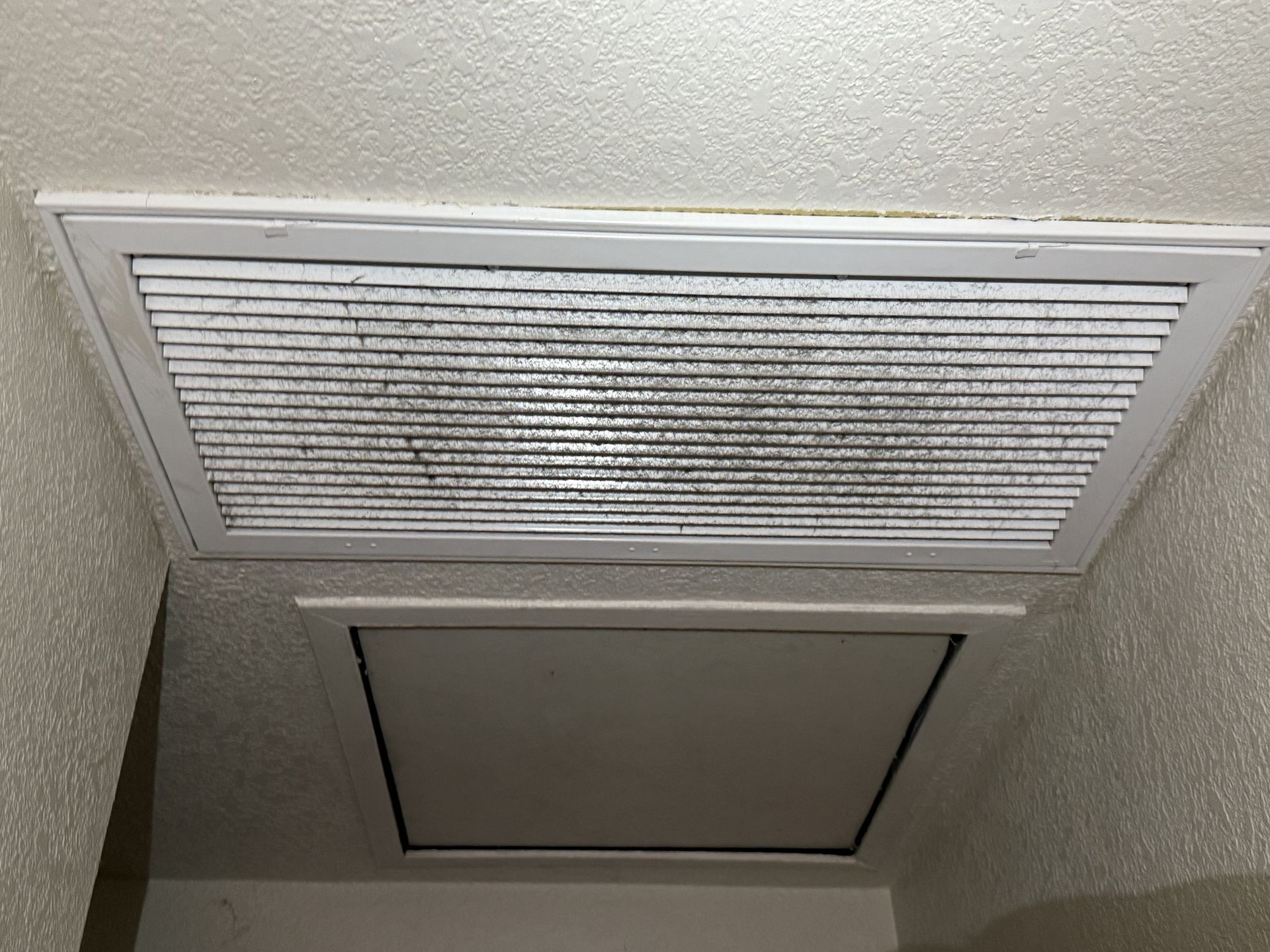 Ceiling with two rectangular HVAC vents, one covered with a filter.