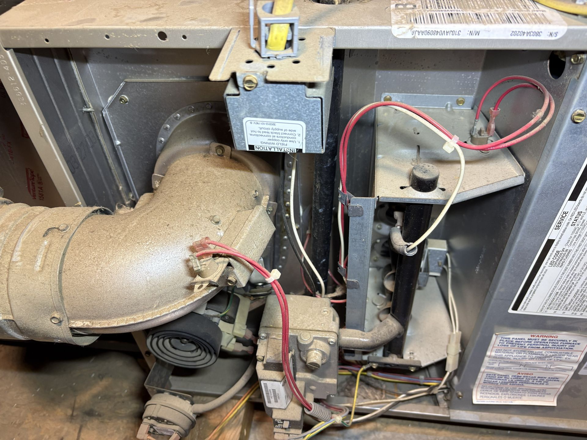 Dusty HVAC blower compartment with wiring, ductwork, and control components exposed