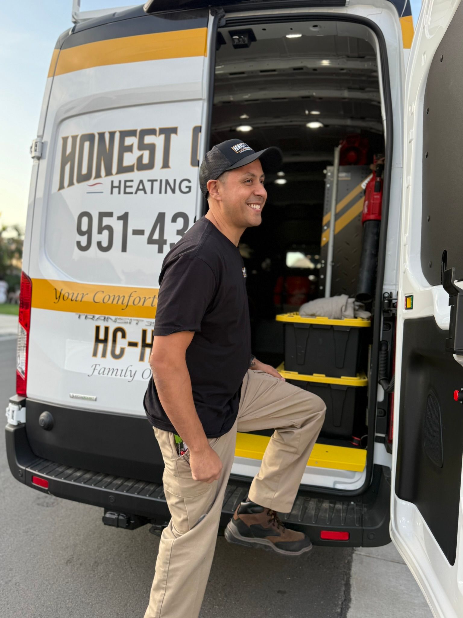 Man smiling while stepping into a white service van labeled “Honest Heating.”