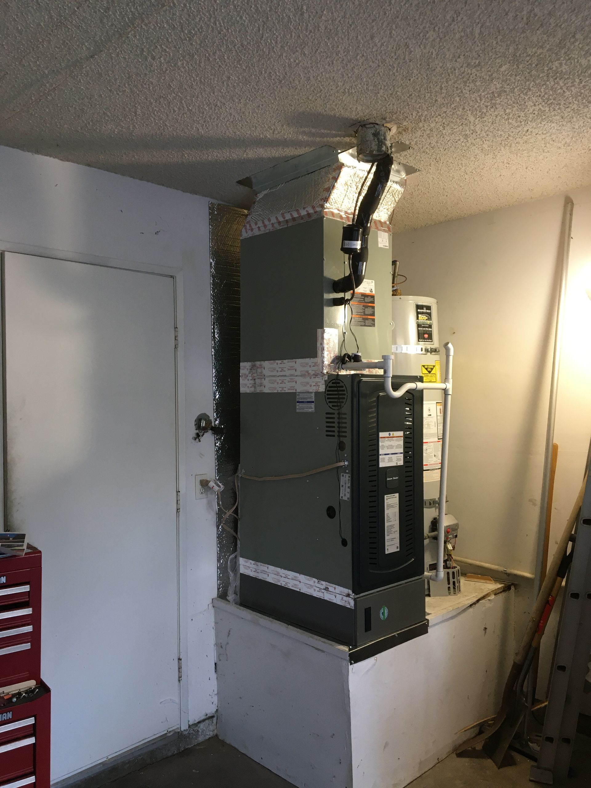 Basement utility area with a furnace, ductwork, and a white door beside it.