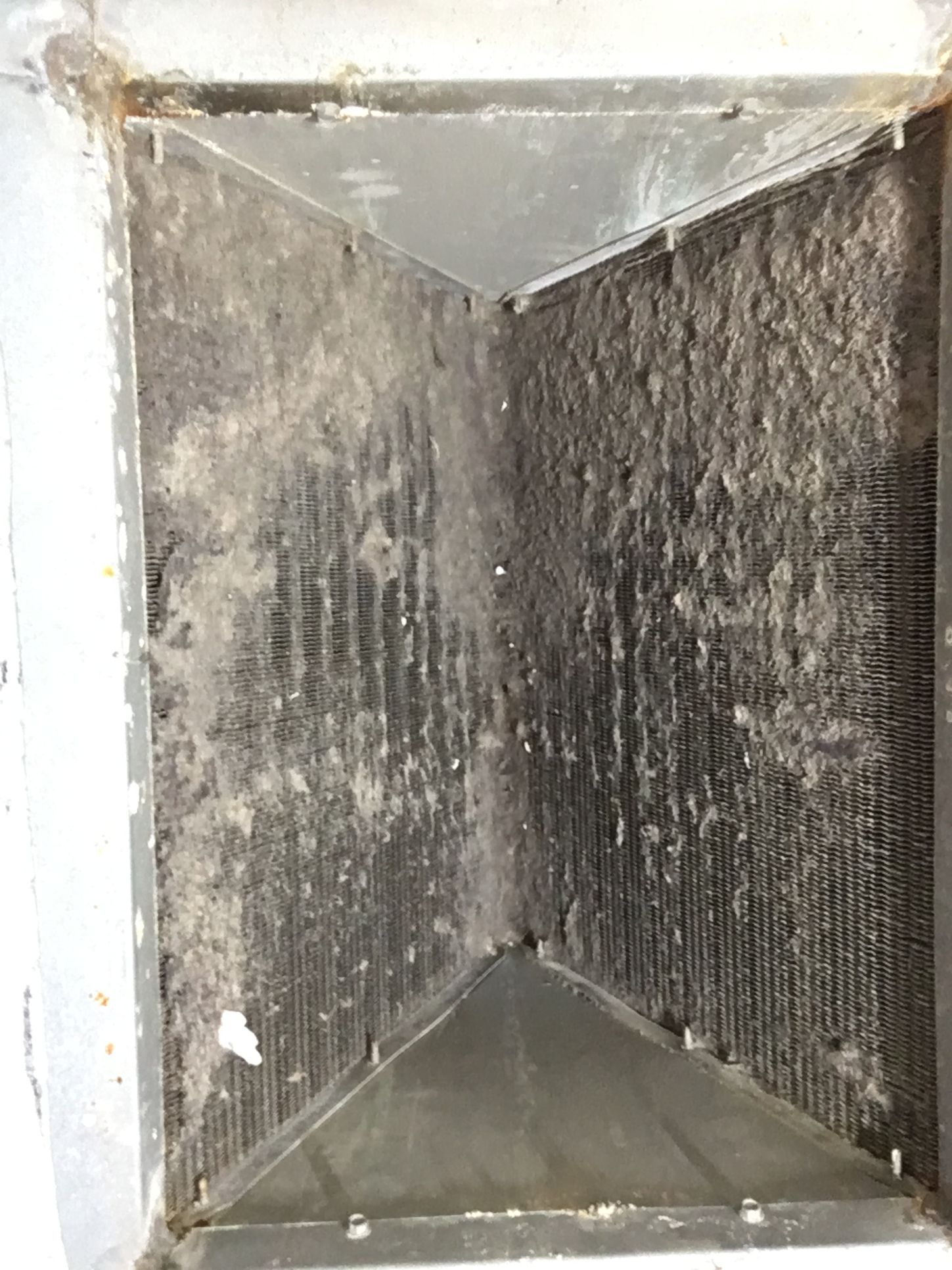 Dirty rectangular air vent with dark dust buildup inside a white frame