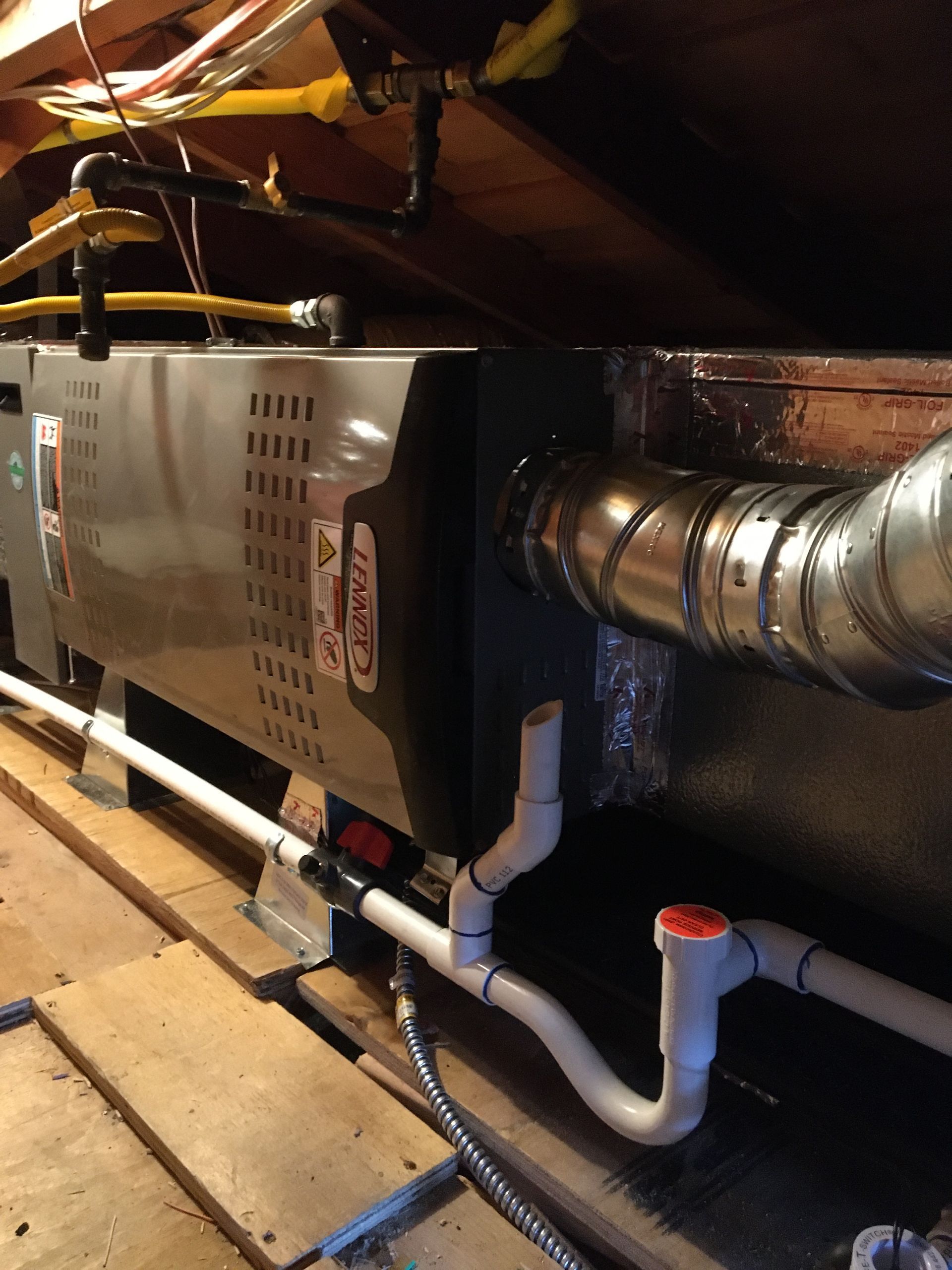 Basement HVAC unit with ductwork, white PVC pipes, and insulated vents under a wooden ceiling