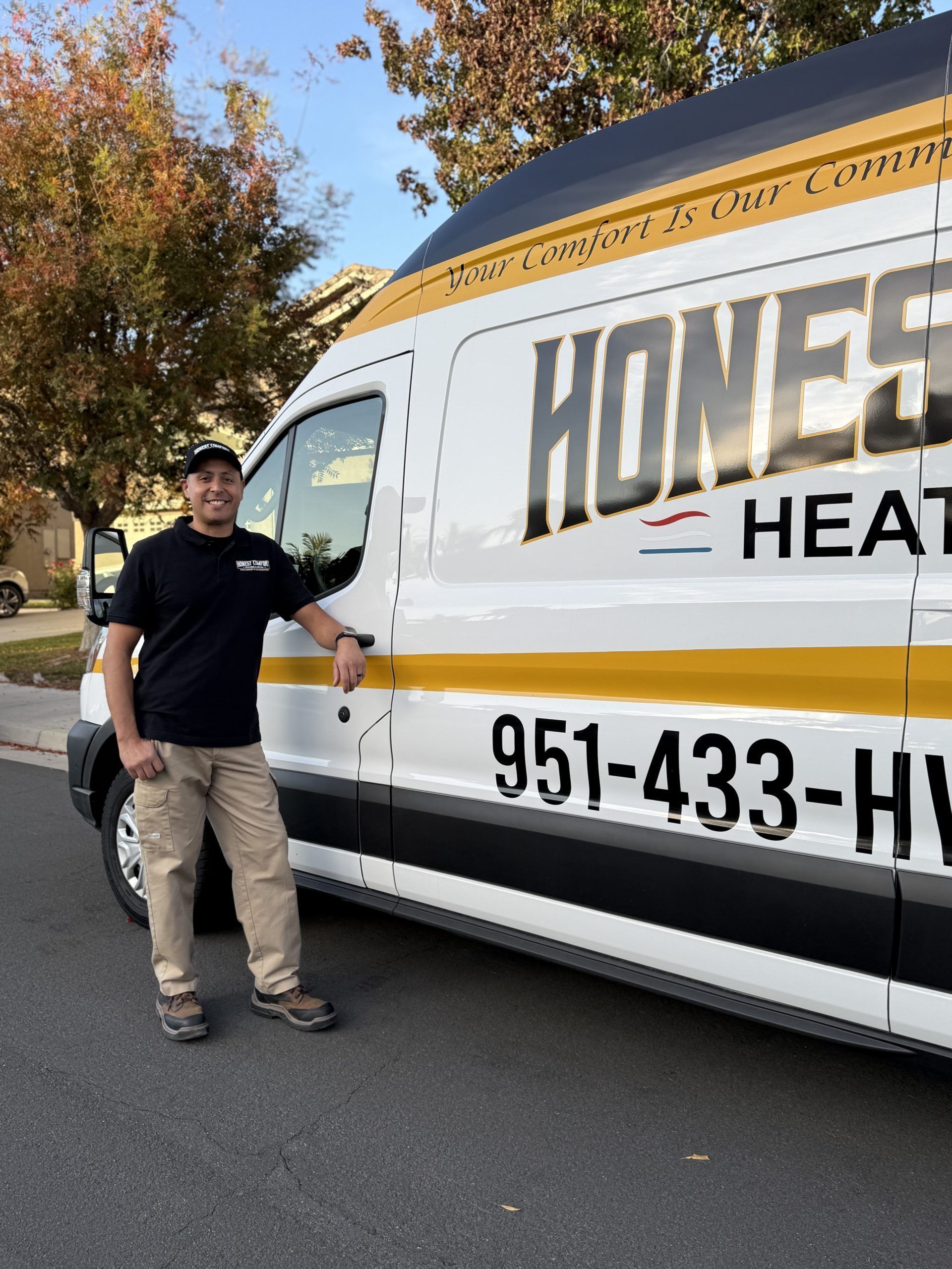 Man standing beside a white and gold HVAC service van on a street