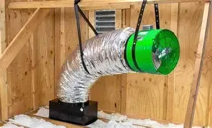 Silver duct with green fan attached inside a wooden enclosure