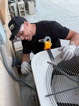 Technician repairing an outdoor air conditioner unit with tools and gloves