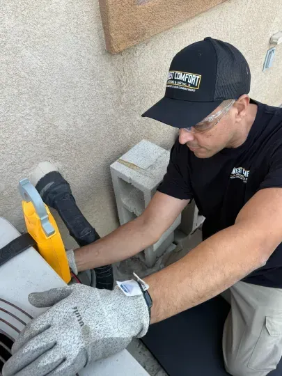 Worker in cap and gloves using a circular saw on a board outdoors.