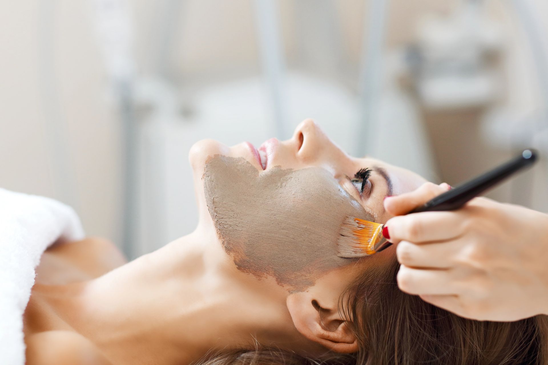 Donna che riceve una maschera facciale applicata con un pennello in una spa.