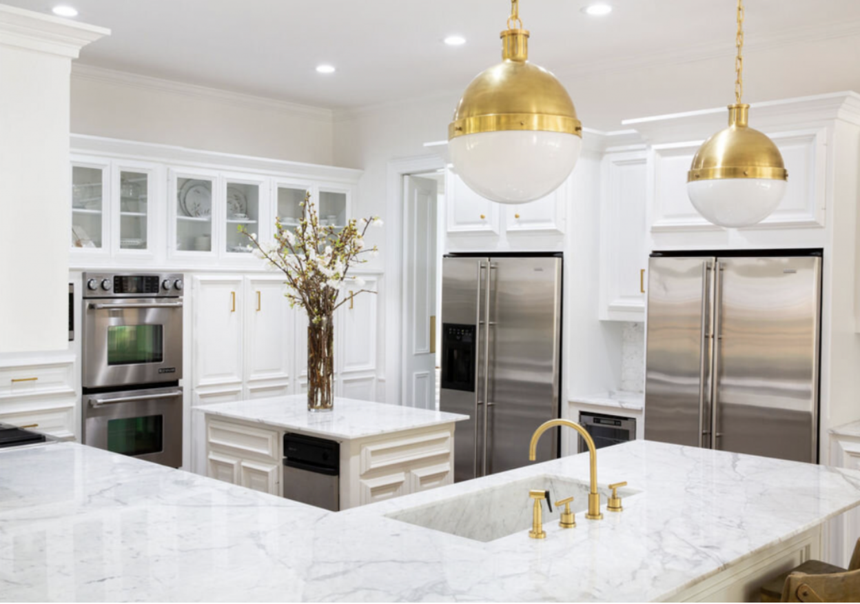 Bright white modern kitchen with marble island, stainless steel appliances, and gold pendant lights