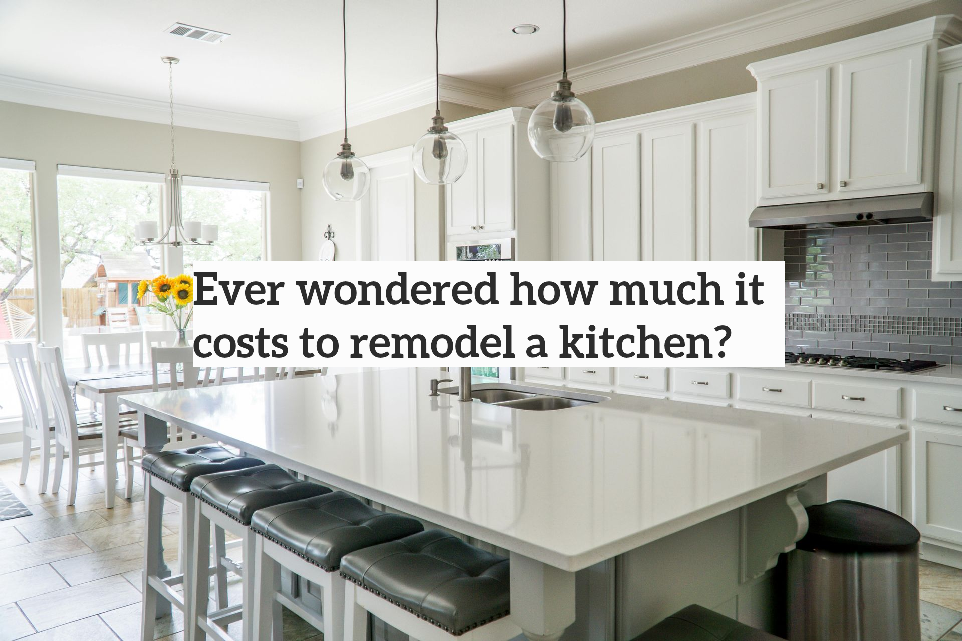 Bright modern kitchen with white cabinets, large island, pendant lights, and a dining area by the windows
