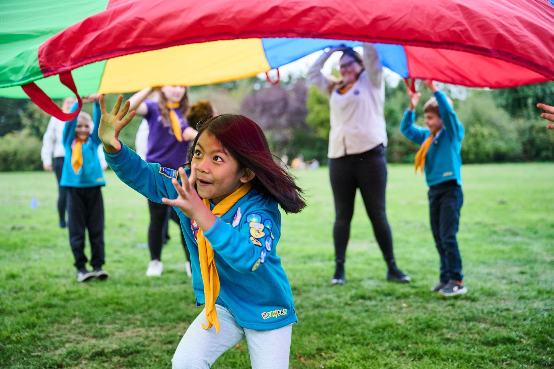 A group of children are playing with a colorful parachute in a park.