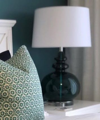 A lamp is sitting on a nightstand next to a bed.