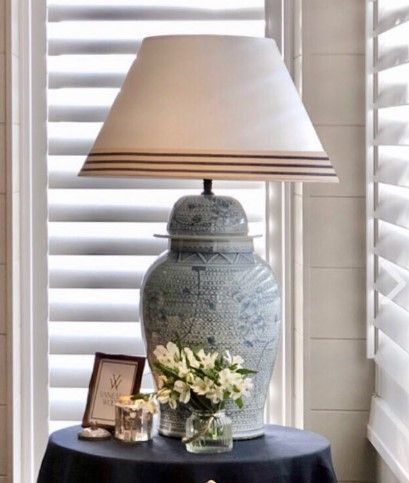 A lamp is sitting on a table next to a vase of flowers.