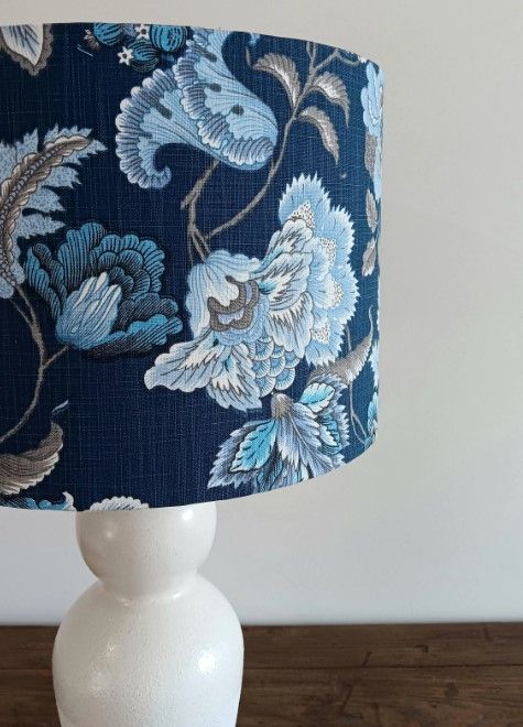 A lamp with a blue floral shade is sitting on a table.