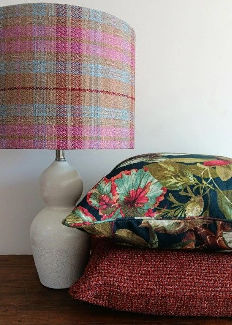 A lamp is sitting on a table next to a stack of pillows.