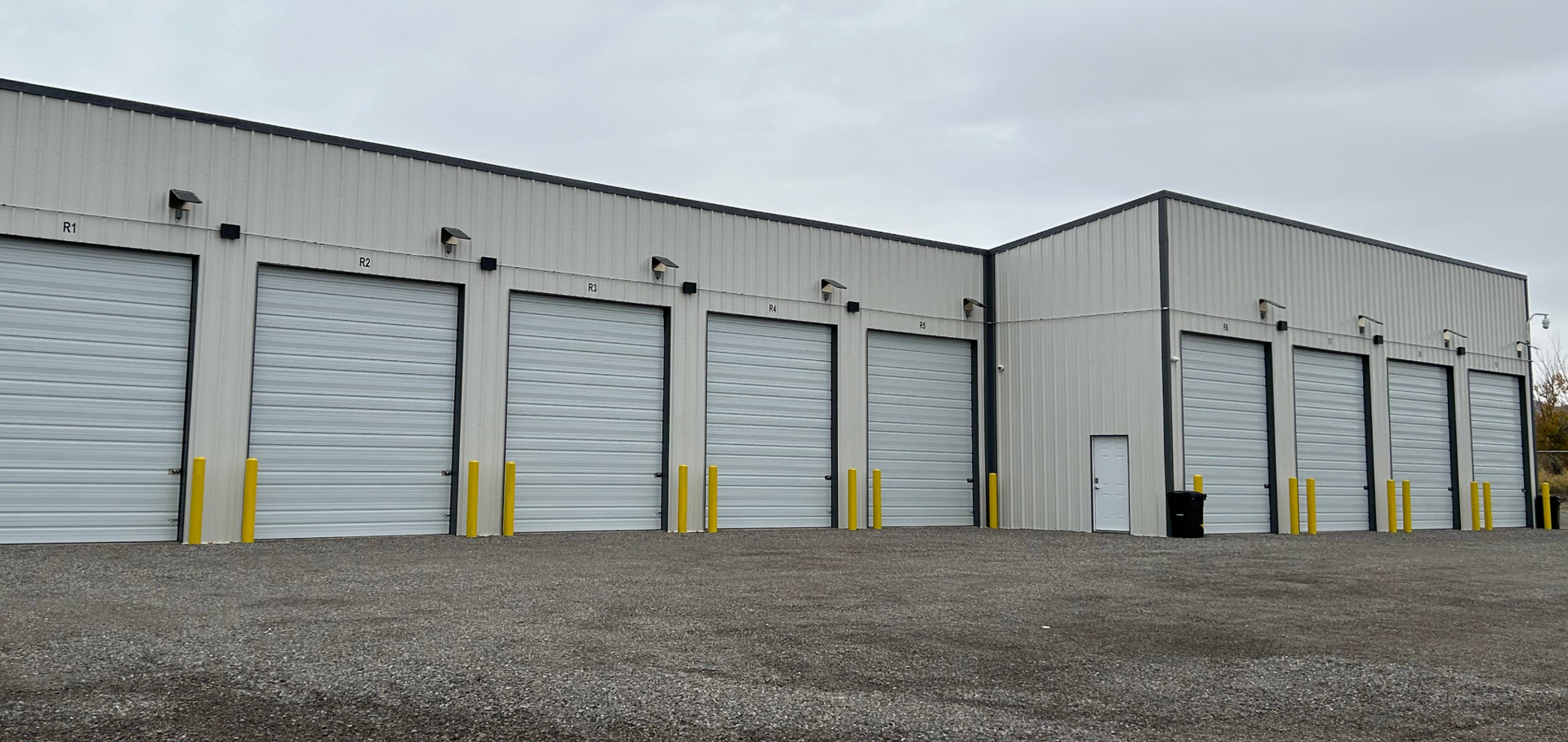 A row of grain silos in a field at sunset.