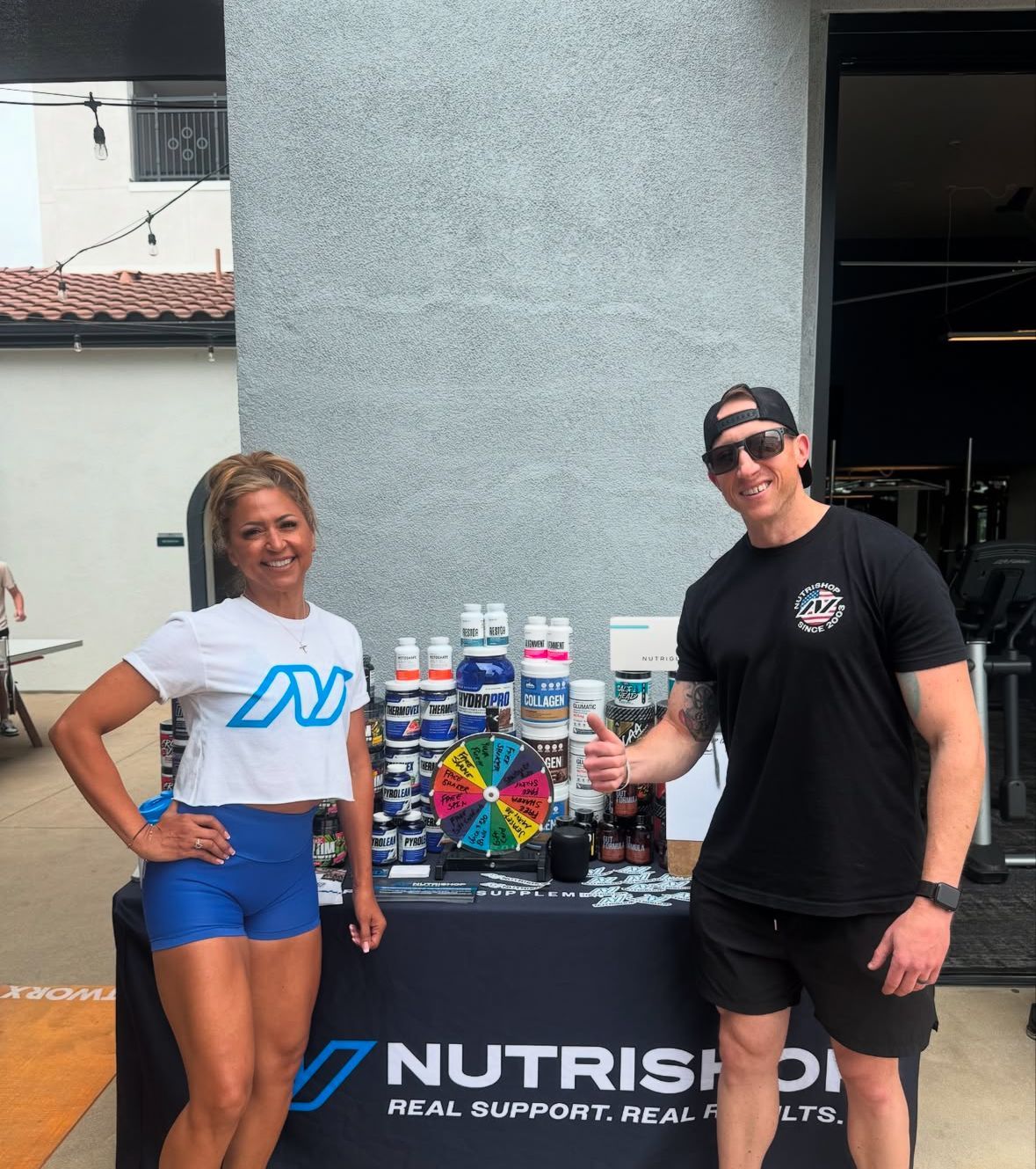 Owners of Nutrishop in front of a table with supplements at The Crossings of Chino Hills 