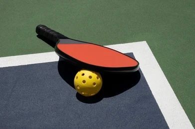 Ping-pong paddle over a yellow ball on a table with a green background
