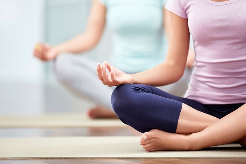 People sitting cross-legged on yoga mats in a bright studio