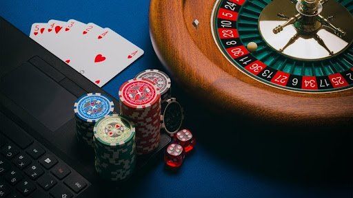 Poker chips, dice, playing cards, and a roulette wheel next to a black laptop. Behavioral Addiction Recovery
