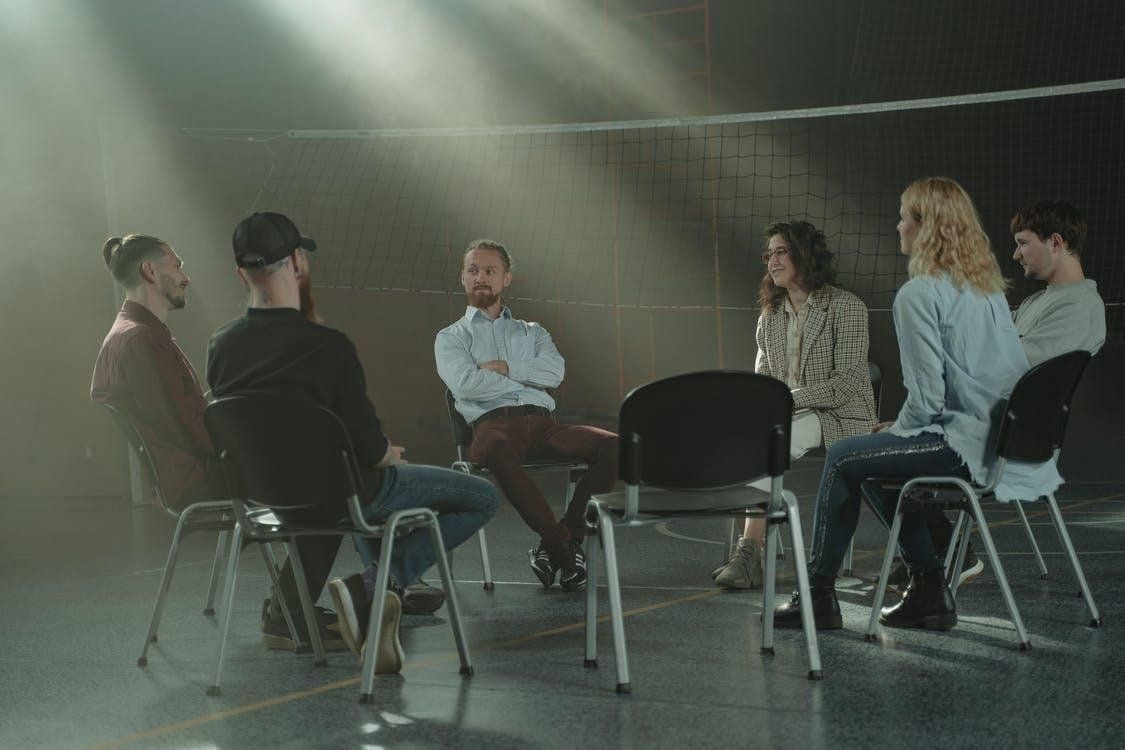 A group of people sitting in a circle and talking. Stages of Addiction Recovery
