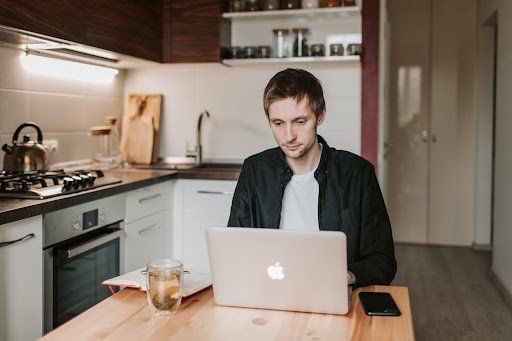A man working from home on a laptop in his kitchen. Ways to Maintain Sobriety