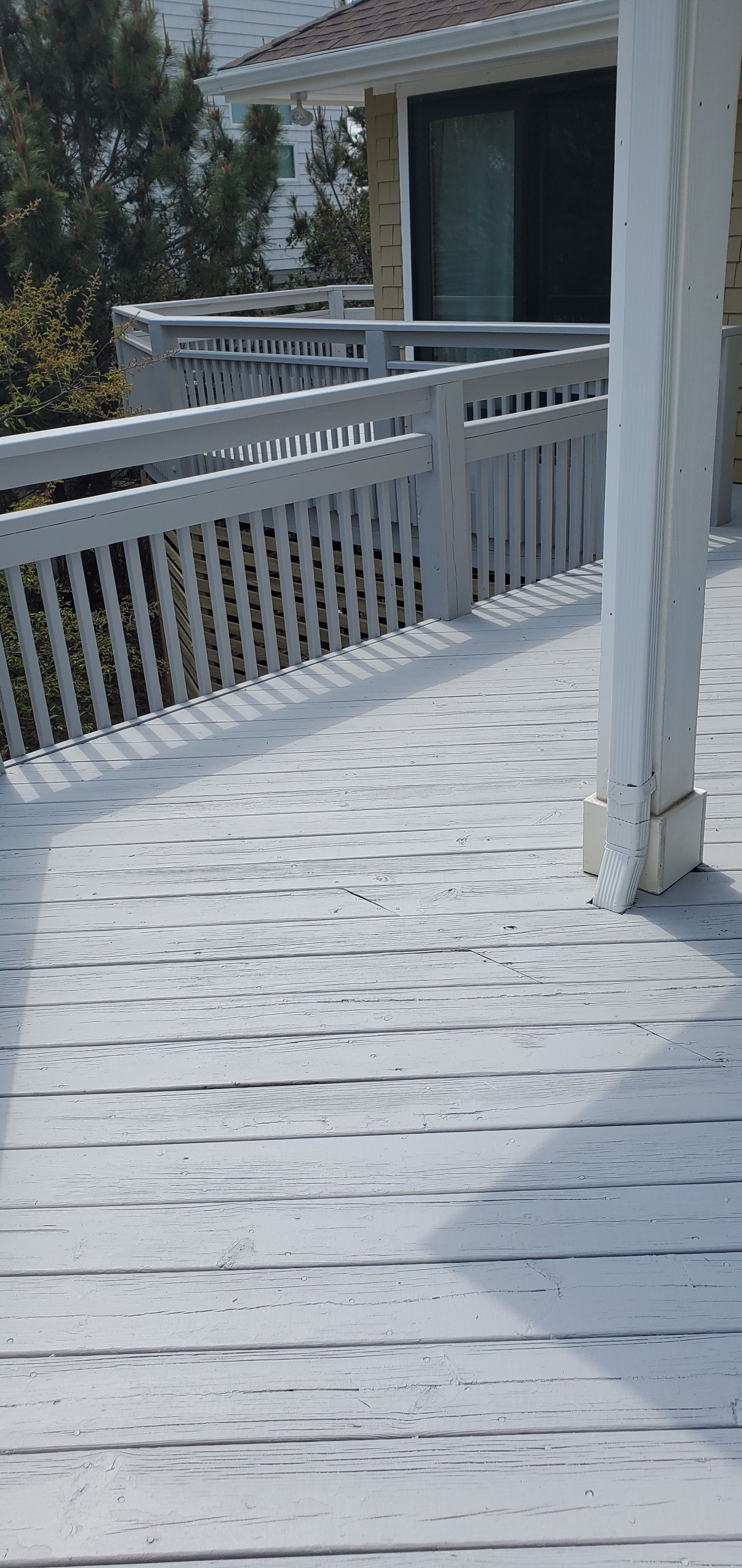 Snow-covered white wooden balcony with railing beside a house