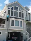 Exterior of a house with a person standing on a ladder near the upper window