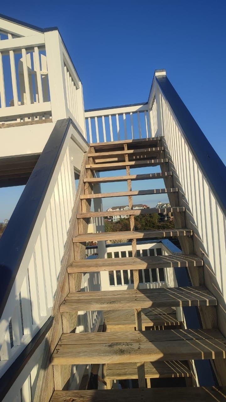 Outdoor wooden staircase with white railings under a clear blue sky