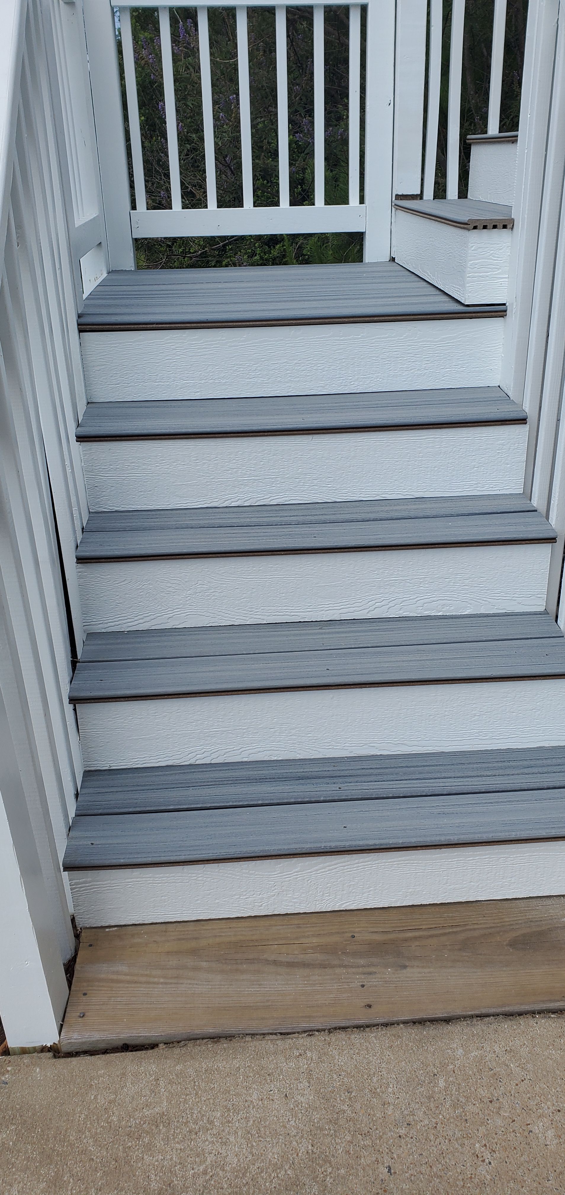 Weathered wooden steps leading up to a porch with white railing and trim