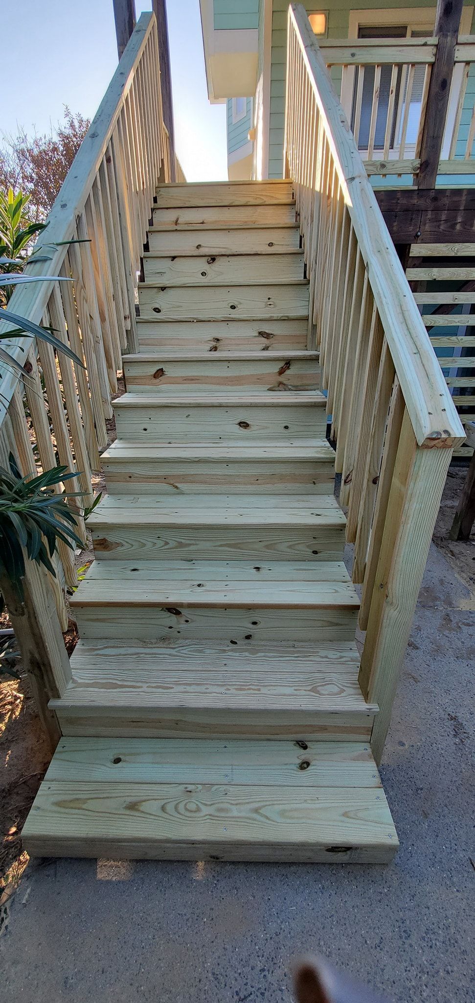 Wooden outdoor staircase leading up to a porch, with railings on both sides.
